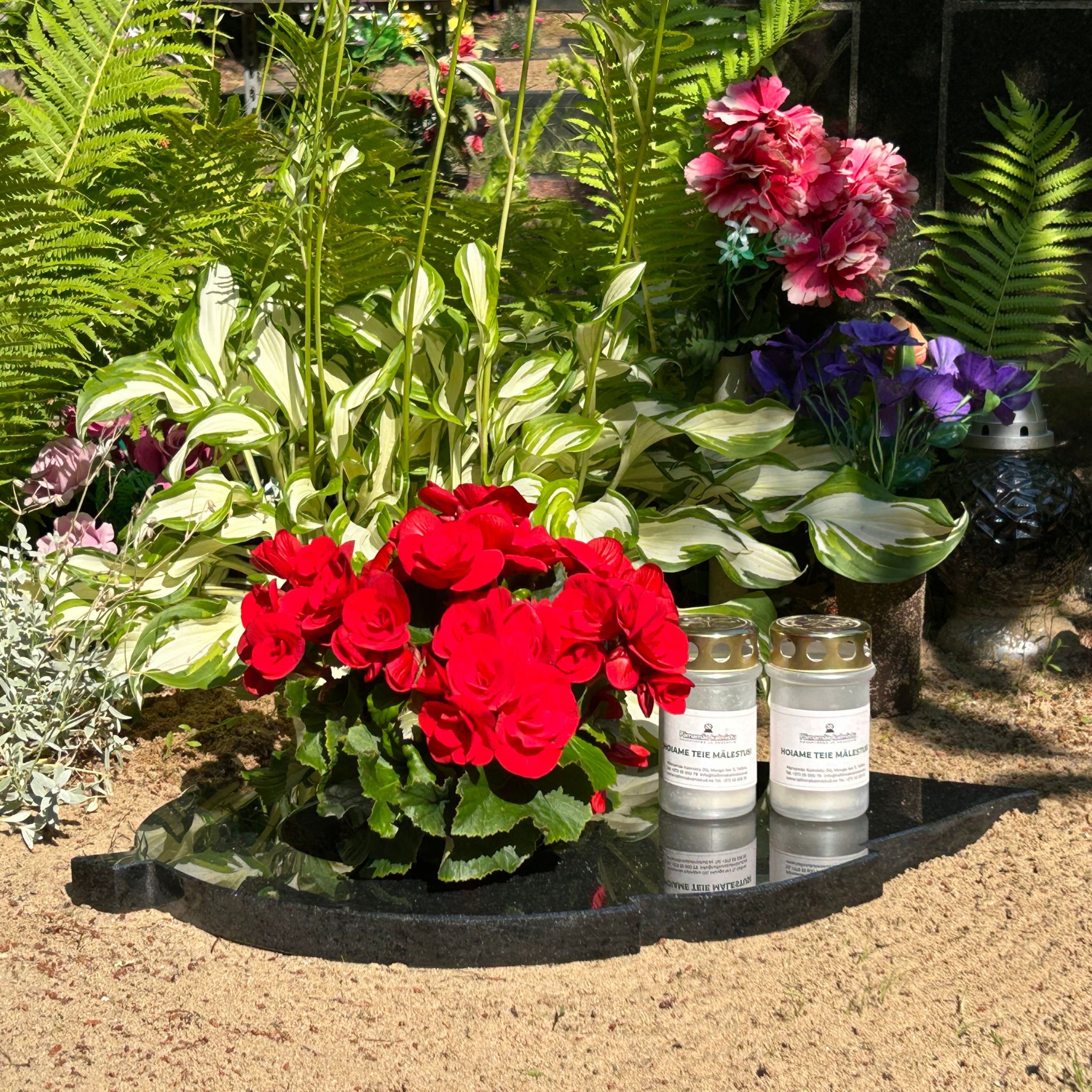 Mustast graniidist lehekujuline lille- ja küünlaalus koos lilledega